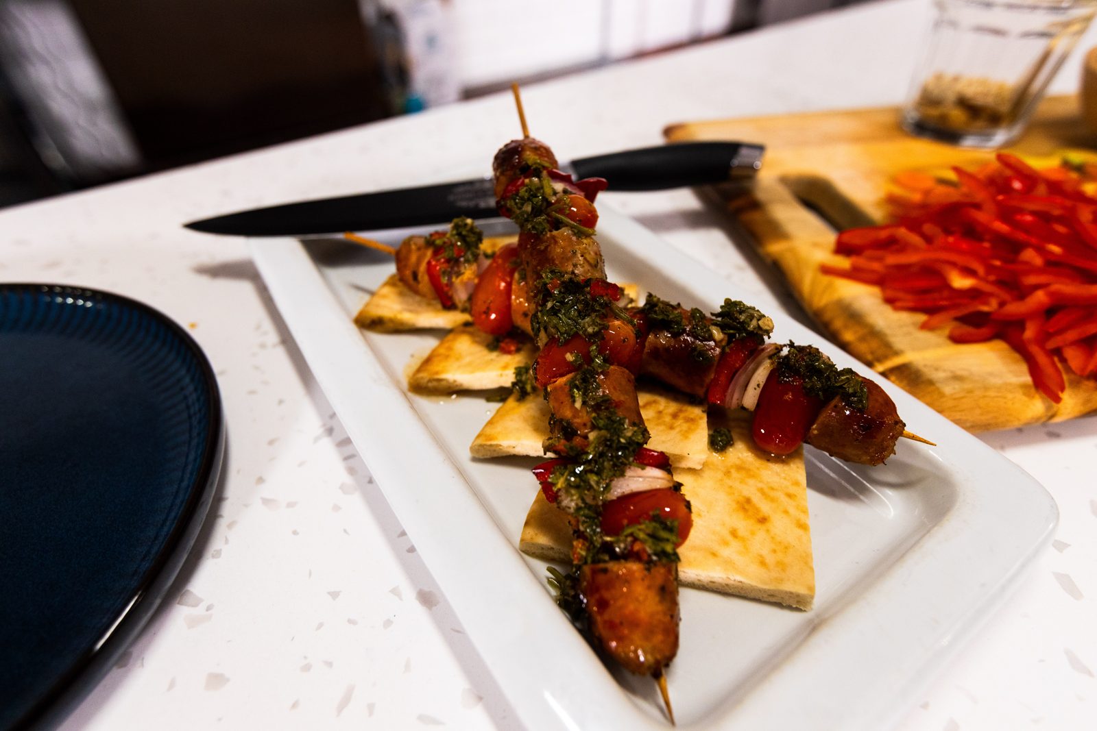 Chimichurri sausage and pepper skewers over warm pita